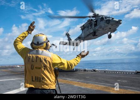 Airman signals an MH-60S Sea Hawk helicopter on the flight deck of USS Bonhomme Richard. Stock Photo