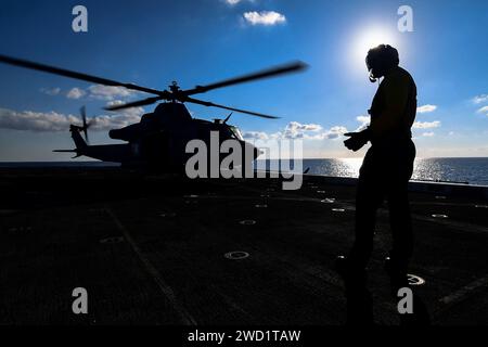 Aviation Support Equipment Technician directs a UH-1Y helicopter on the flight deck of USS San Diego. Stock Photo