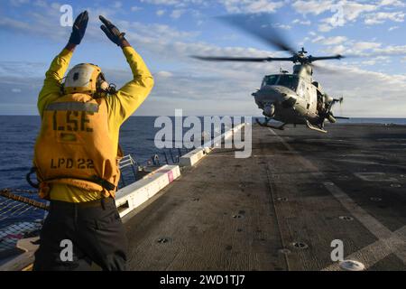 Aviation Boatswain's Mate signals a UH-1Y Venom helicopter to land on the flight deck of USS San Diego. Stock Photo