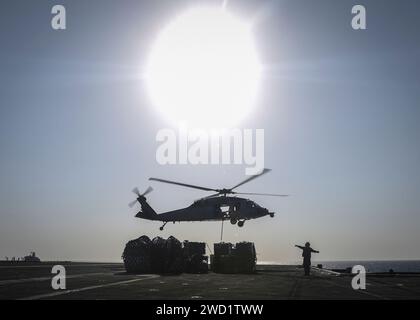 An MH-60S Sea Hawk helicopter delivers supplies to the aircraft carrier USS Nimitz. Stock Photo