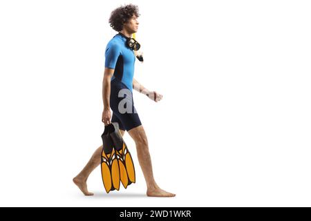 Full length profile shot of a guy in a diving suit carrying fins and walking isolated on white background Stock Photo