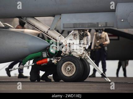 Aviation Boatswain's Mate places a hold-back bar on an F/A-18E Super Hornet as it prepares to launch. Stock Photo