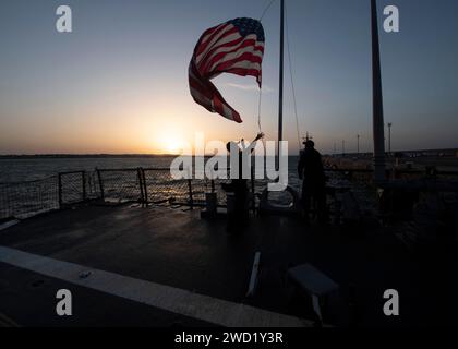 Sailors raise the national ensign aboard the guided-missile destroyer USS Donald Cook. Stock Photo