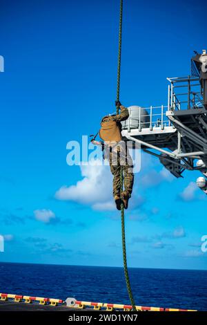 A U.S. Marine fast-ropes from an MV-22 Osprey aboard USS Makin Island. Stock Photo