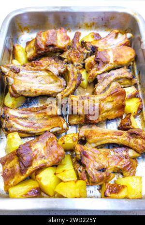 Baked pork ribs with potatoes in an oven tray. Stock Photo