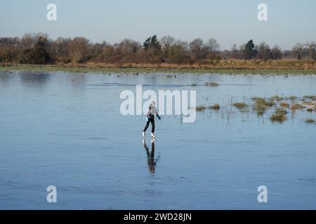 Fen skaters on a frozen flooded field in Upware, Cambridgeshire. The UK will remain in a cold snap until the weekend with freezing temperatures set to plummet even further across much of the country. Picture date: Thursday January 18, 2024. Stock Photo