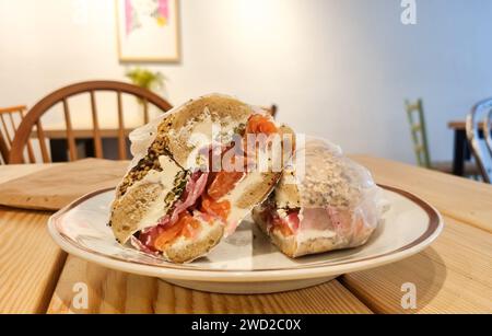 A closeup of a bagel with salmon on a wooden table in a restaurant. Stock Photo