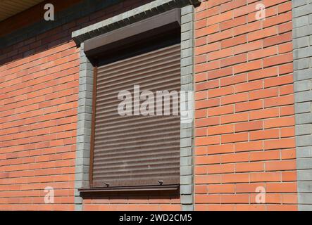 Rolling shutters brick house windows protection. Brick house with metal roller shutters on the windows Stock Photo