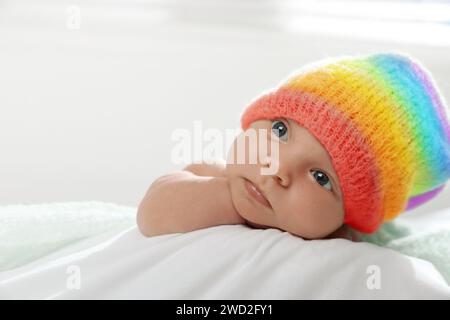National rainbow baby day. Cute child in hat with colorful pattern on blanket Stock Photo