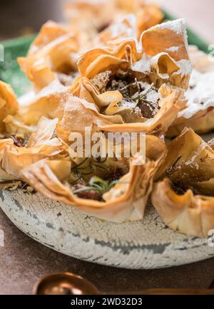 Phyllo pastry  cups with brie, jam, nuts sprinkled with powder sugar . Delicious filo pastry dessert Stock Photo