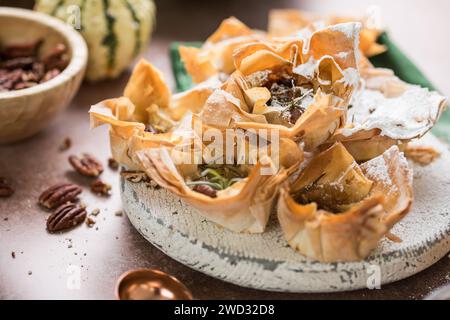 Phyllo pastry  cups with brie, jam, nuts sprinkled with powder sugar . Delicious filo pastry dessert Stock Photo