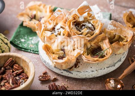 Phyllo pastry  cups with brie, jam, nuts sprinkled with powder sugar . Delicious filo pastry dessert Stock Photo