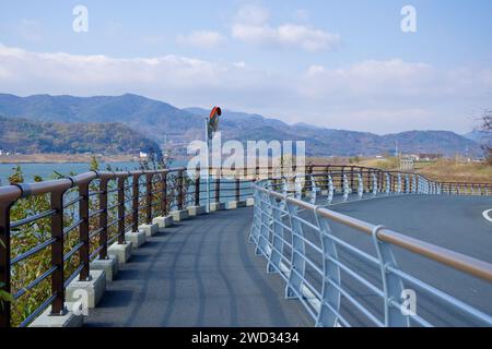 Gumi City, South Korea - November 17th, 2023: A curving bike path by the Nakdong River, featuring a concave safety mirror and fences on both sides, sa Stock Photo