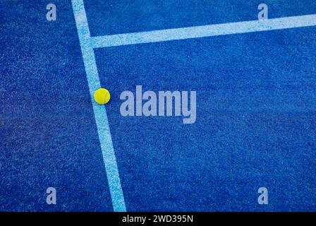 Closeup of one yellow tennis ball with paddle tennis and white lines on blue court. Horizontal sport poster, greeting cards, headers, website Stock Photo