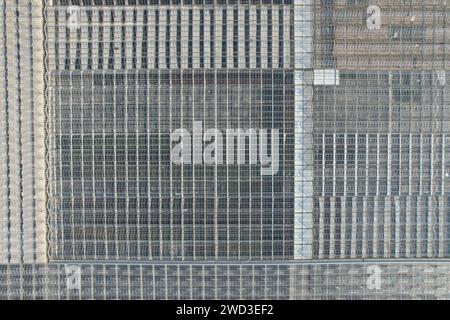 Glass greenhouses from above in sunny weather, big glass houses from aerial panorama landscape view,intensive modern agriculture in Europe Stock Photo