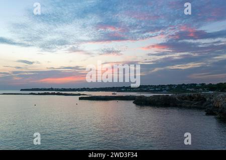 Binibèquer Vell, Menorca, Balearic Islands, Spain. View along rocky coast after sunset, pink clouds in sky. Stock Photo
