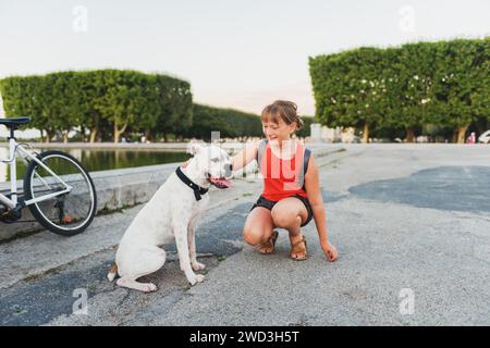 Kid girl  playing with a dog white boxer outside Stock Photo