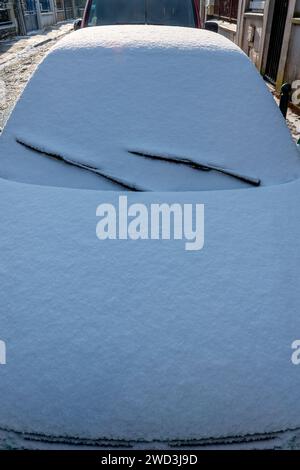 Close-up of the front of a car covered in a layer of snow on the street on a cold winter morning Stock Photo
