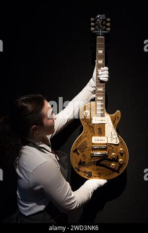 LONDON, UNITED KINGDOM - JANUARY 18, 2023: A staff member holds Gibson, Nashville, Tennessee, 2021, a solid-body electric guitar, Les Paul Standard ‘Gold Top', estimate: £20,000-40,000 signed by Mark Knopfler, Eric Clapton, Jeff Beck, David Gilmour, Pete Townshend, Roger Daltrey, Slash, Ronnie Wood, Brian May, Sting, Ringo Starr, Bruce Springsteen, The Edge, Joan Jett, Nile Rodgers, as well as many others during a photocall at Christie's auction house showcasing the highlights from the personal collection of Mark Knopfler, frontman of the iconic British band, Dire Straits, in London, United Ki Stock Photo