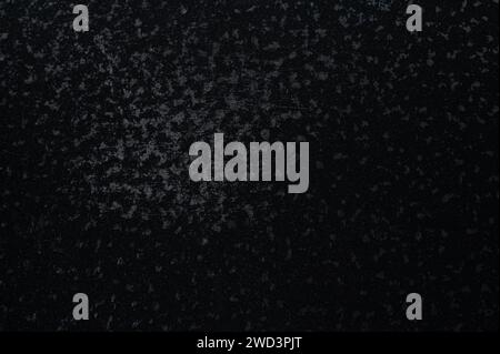 Black plastic pattern background with wear spots close up view Stock Photo