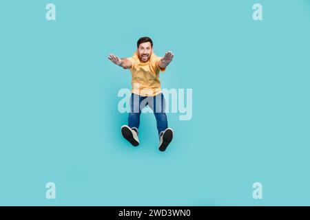 Full body photo of young guy purposeful muscular sportsman in casual clothes jumping doing workout isolated on cyan color background Stock Photo