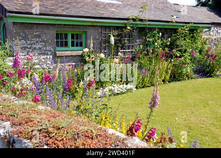 Bungalow with small garden with lawn surrounded by colorful flowers Stock Photo