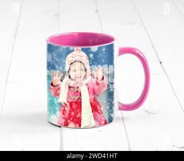 Pink cup with bright pink handle sitting on the table, with a print of girl Stock Photo