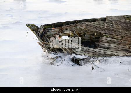 Closeup of bow of old wooden boat broken and surrounded by ice Stock Photo