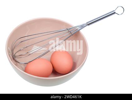 Manual egg beater and three eggs in a ceramic bowl Stock Photo