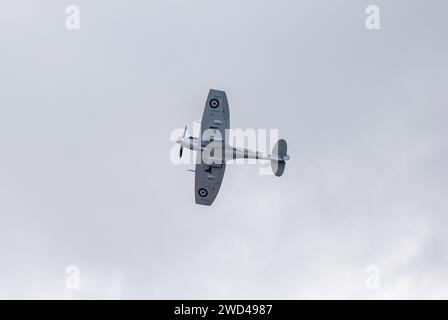 Spitfire flying in the clouds at Duxford flying legends airshow. Clipped wing super marine spitfire. Stock Photo