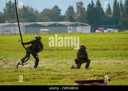 Special forces soldiers running across battlefield after descending from a helicopter during reenactment. SWAT police Stock Photo