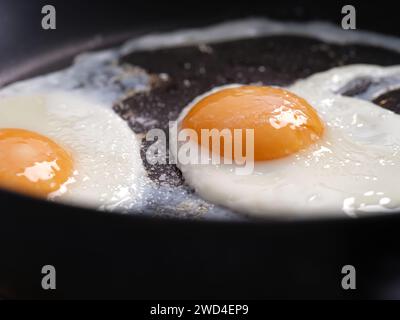 Two fried eggs seasoned with sea salt in a frying pan. Close up. Stock Photo