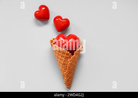 Creative composition with waffle cone and red hearts on blue background. Valentine's day celebration Stock Photo