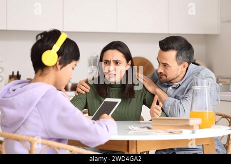 Upset parents with their teenage son at table in kitchen. Family problem concept Stock Photo