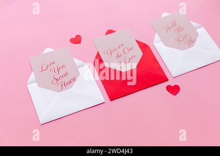 Two unsealed envelopes placed alongside paper hearts on a vibrant pink backdrop Stock Photo