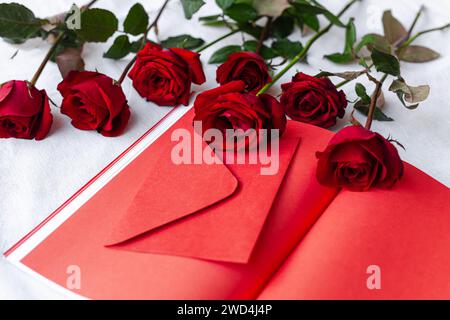 Red roses placed next to an open book on a pristine white fabric Stock Photo