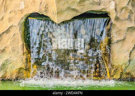A small decorative waterfall in the garden. Landscape design. Small artificial waterfall in man made tropical garden Stock Photo