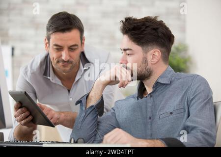 diverse businessmen talking using digital tablet sit at office desk Stock Photo