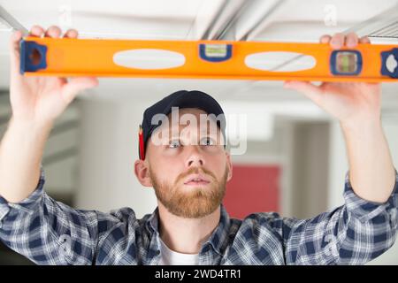 house renovation worker checking the alignment of a ceiling Stock Photo