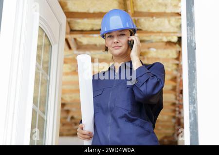 woman builder with blueprints using smart phone Stock Photo