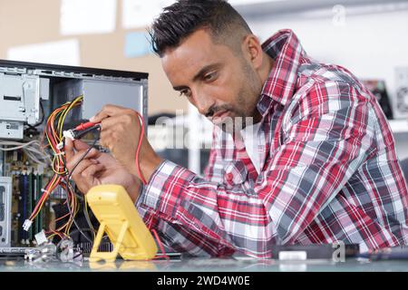 man uses a multimeter voltmeter to check a pc Stock Photo