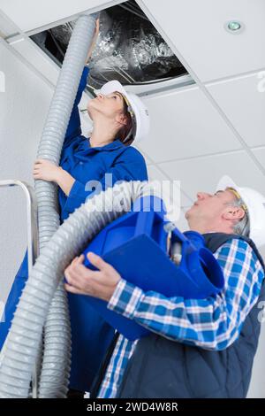 female electrician installing ventilation in ceiling Stock Photo