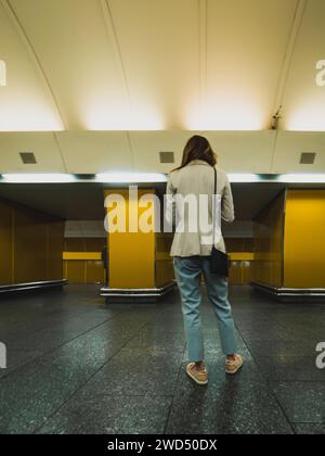 woman at metro station seen from behind Stock Photo