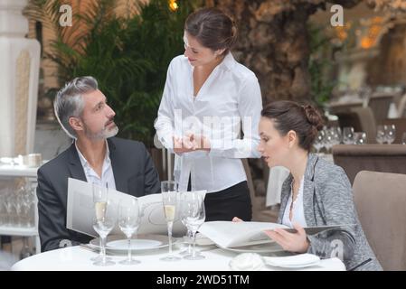 smiling female waiter serving guests in restaurant Stock Photo