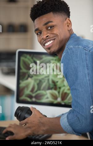 man using computer and holding camera lens Stock Photo