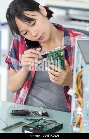 female on the phone fixing a computer Stock Photo