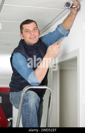 male technician installing surveillance camera on ceiling Stock Photo