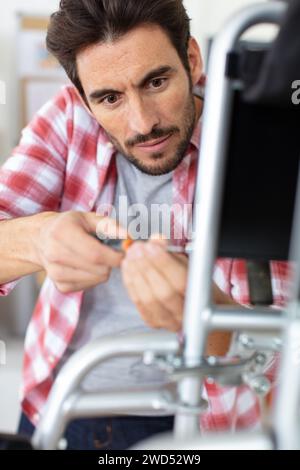 positive handsome young man using screwdriver for fixing something Stock Photo