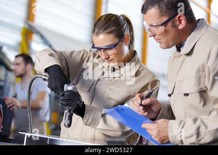 female apprentice engineer working on drill in factory Stock Photo