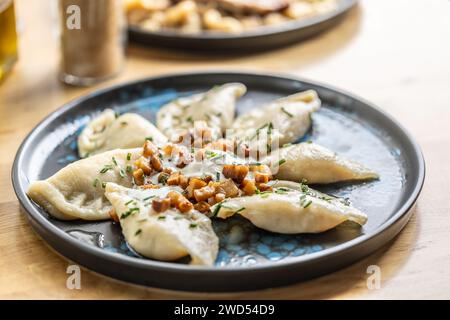 Filled pirohy dish served with fried bacon, fresh chive, and sour cream. Stock Photo